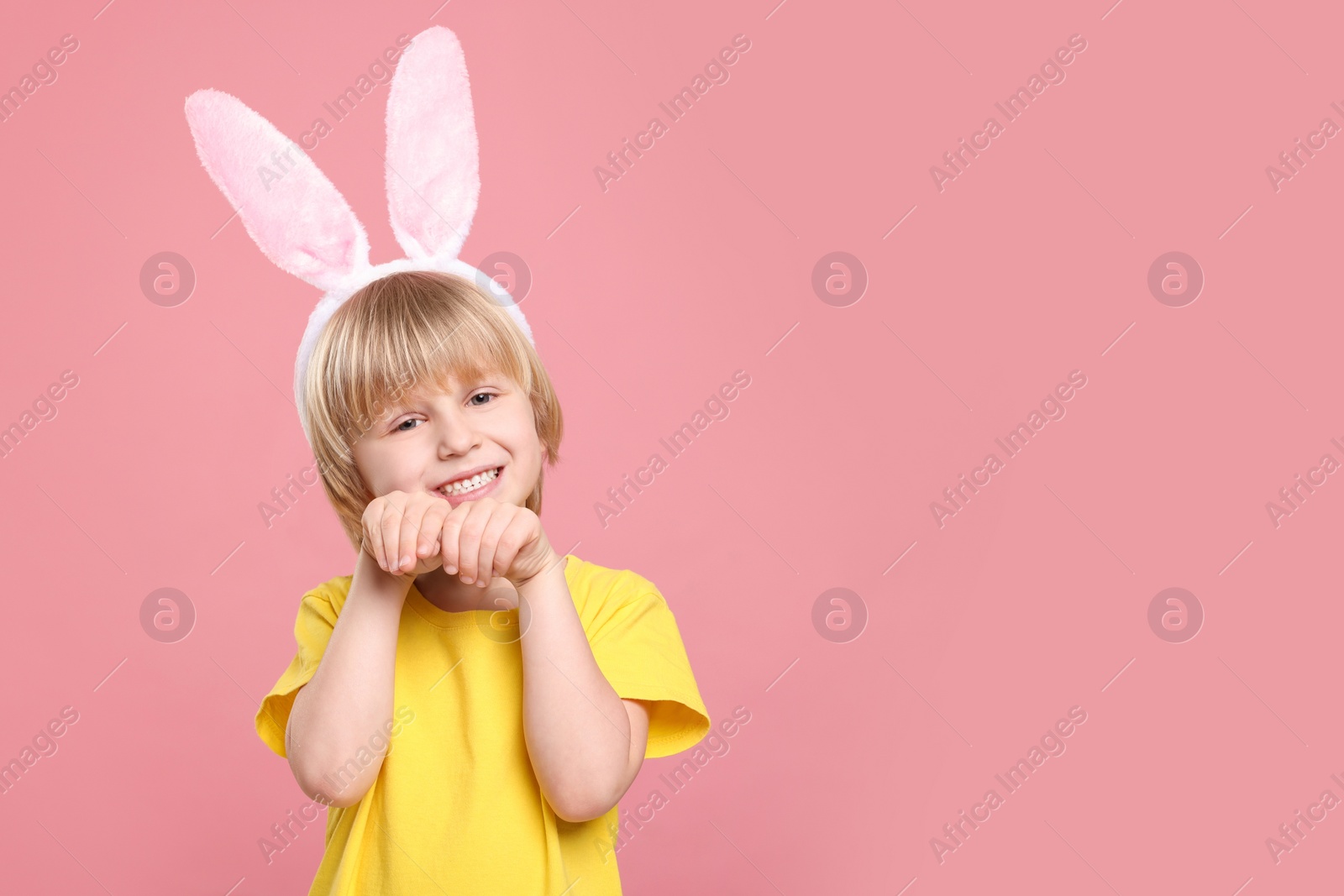 Photo of Happy boy wearing bunny ears headband on pink background, space for text. Easter celebration