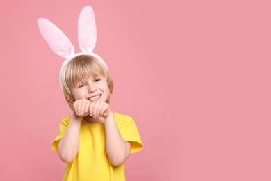 Photo of Happy boy wearing bunny ears headband on pink background, space for text. Easter celebration