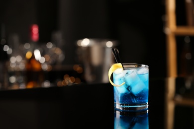 Glass of fresh alcoholic cocktail on bar counter, space for text