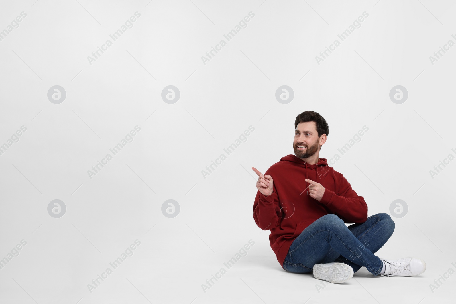 Photo of Happy man pointing at something on white background. Space for text