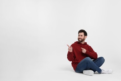 Photo of Happy man pointing at something on white background. Space for text