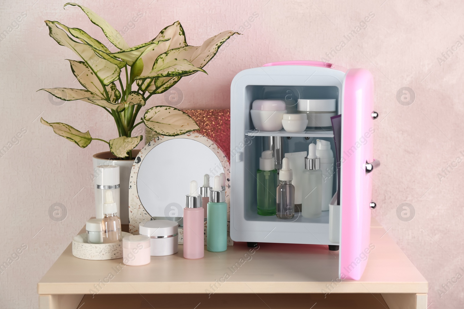 Photo of Cosmetics refrigerator and skin care products on table