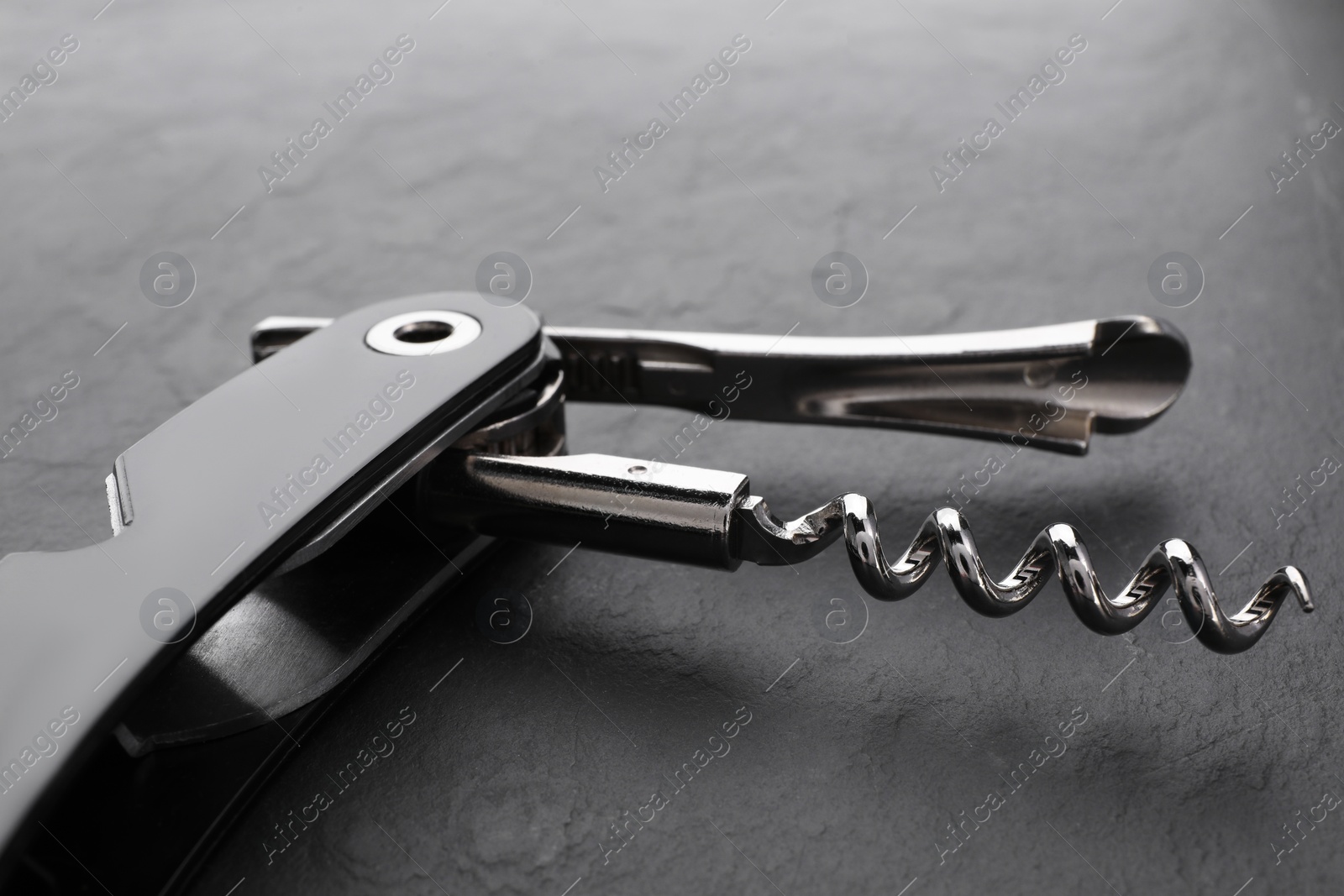 Photo of One corkscrew (sommelier knife) on grey textured table, closeup