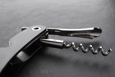 One corkscrew (sommelier knife) on grey textured table, closeup