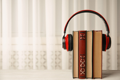 Photo of Books and headphones on white wooden table, space for text