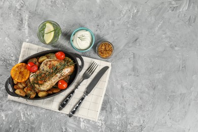 Photo of Delicious chicken, vegetables, drink with tarragon and salad dressings served on grey table, flat lay. Space for text