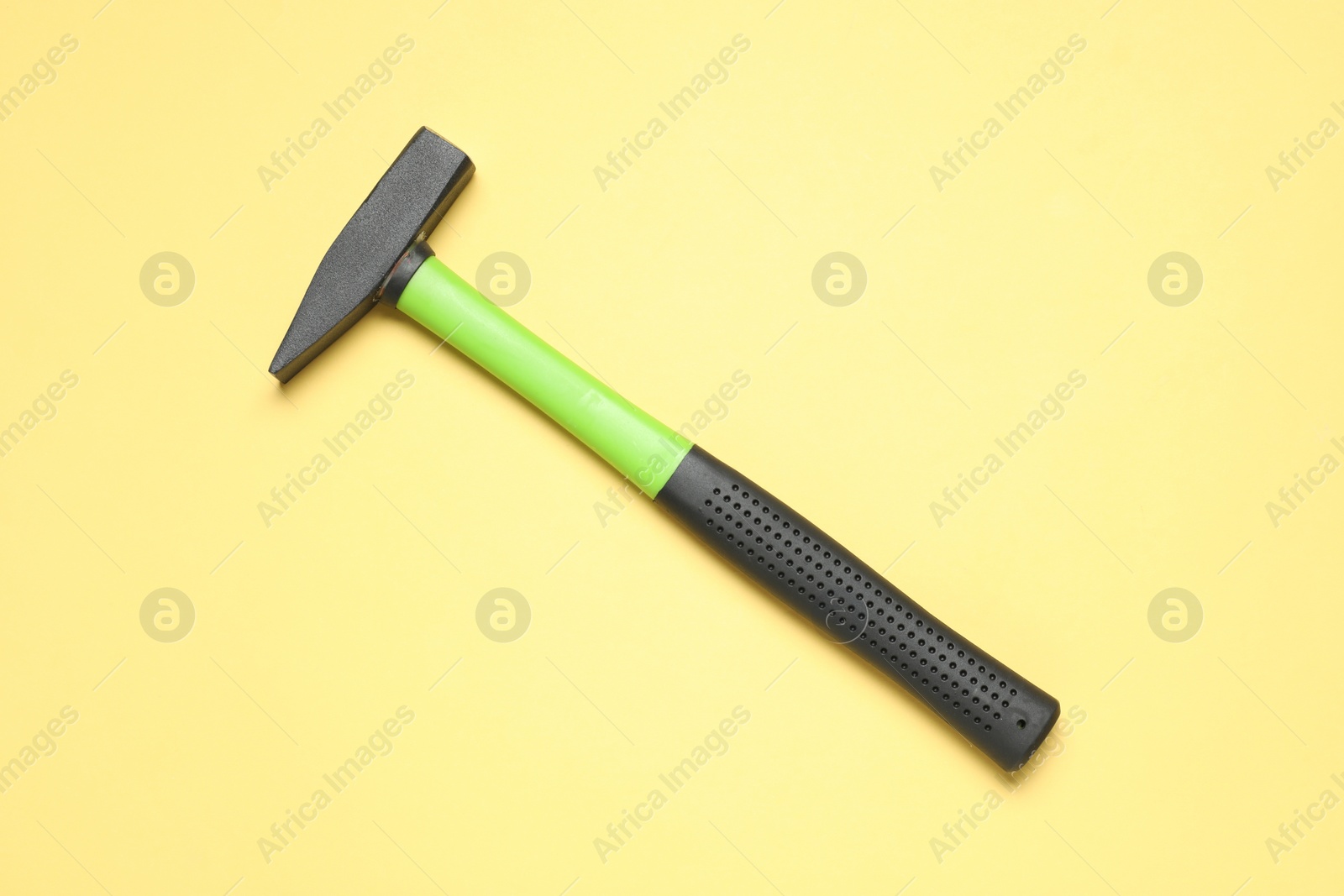 Photo of New hammer with rubber handle on yellow background, top view