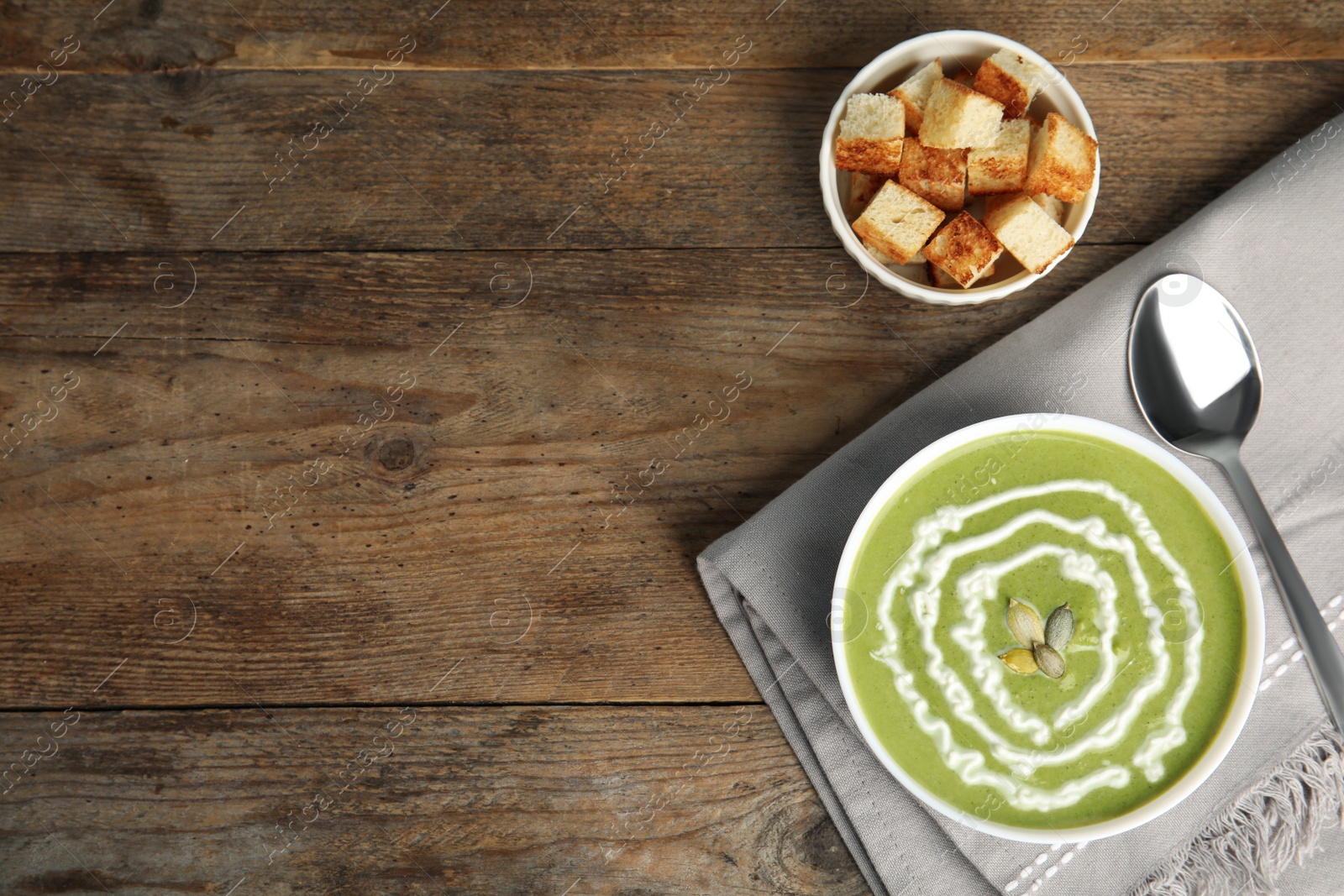 Photo of Delicious broccoli cream soup served on wooden table, flat lay. Space for text