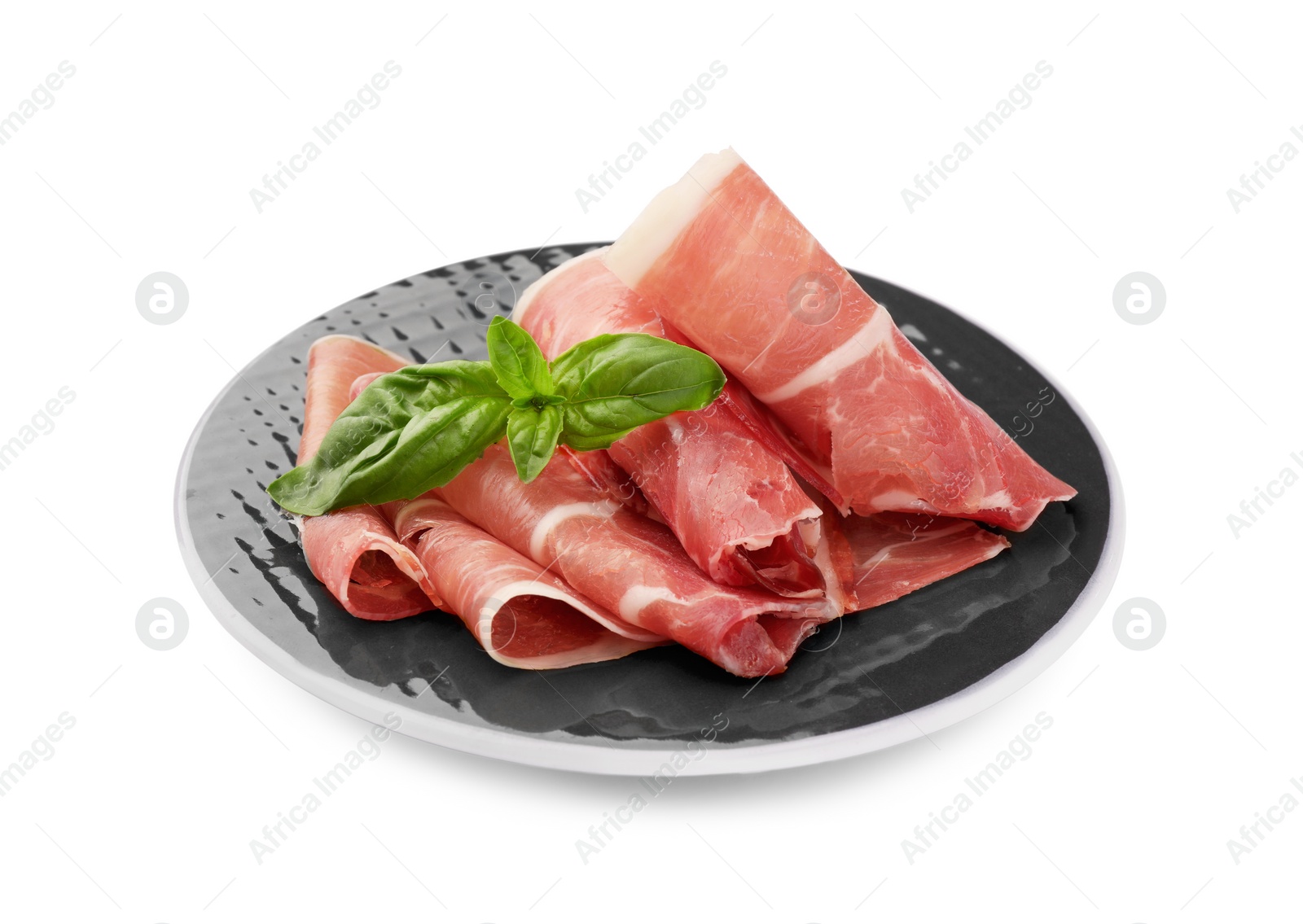 Photo of Plate with rolled slices of delicious jamon and basil isolated on white