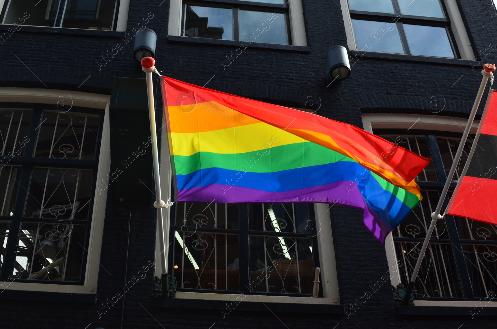 Photo of Rainbow flag fluttering on modern building outdoors