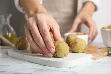 Photo of Woman making falafel balls at white marble table, closeup