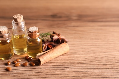 Anise essential oil and spices on wooden table, space for text