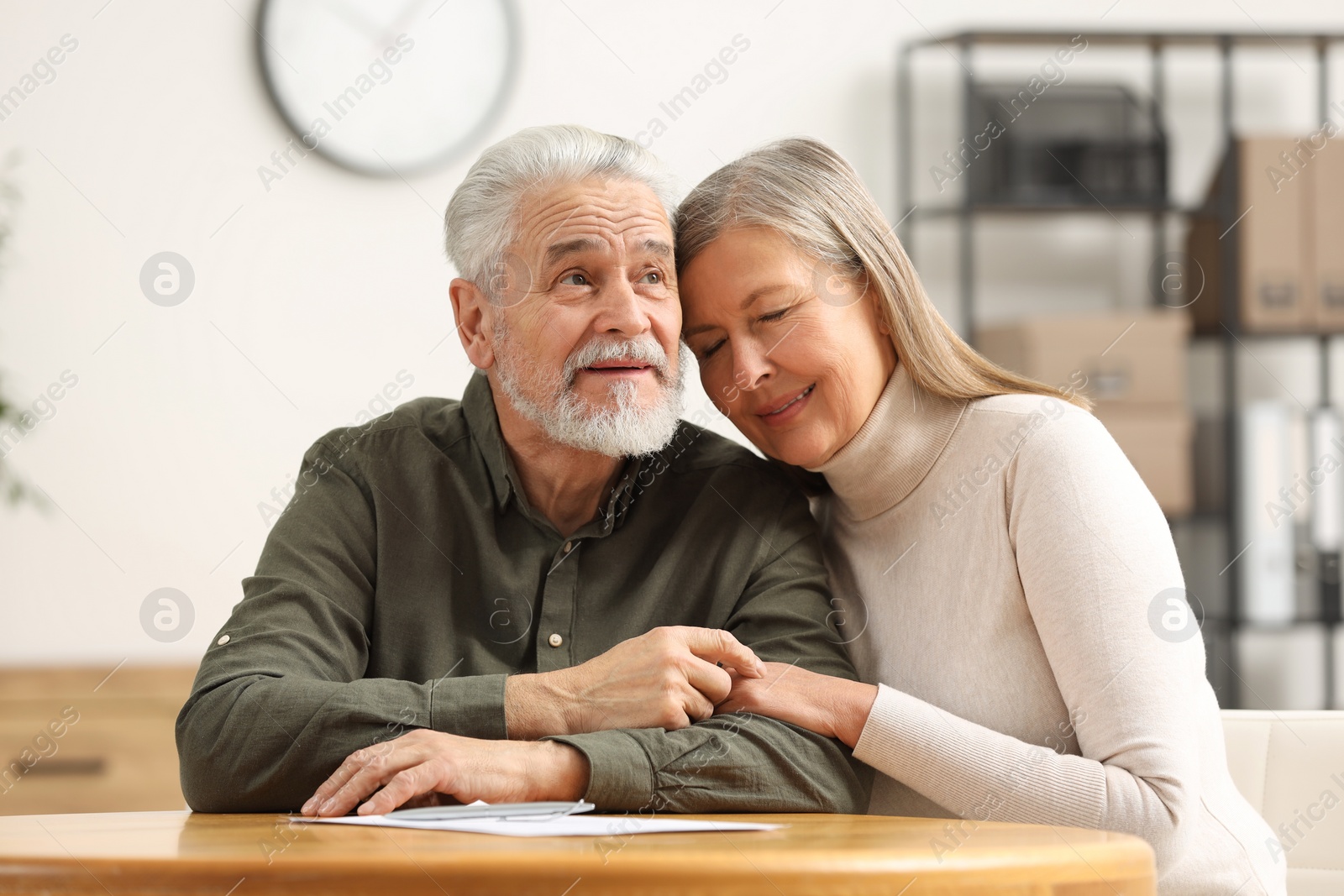 Photo of Happy senior couple signing Last Will and Testament indoors