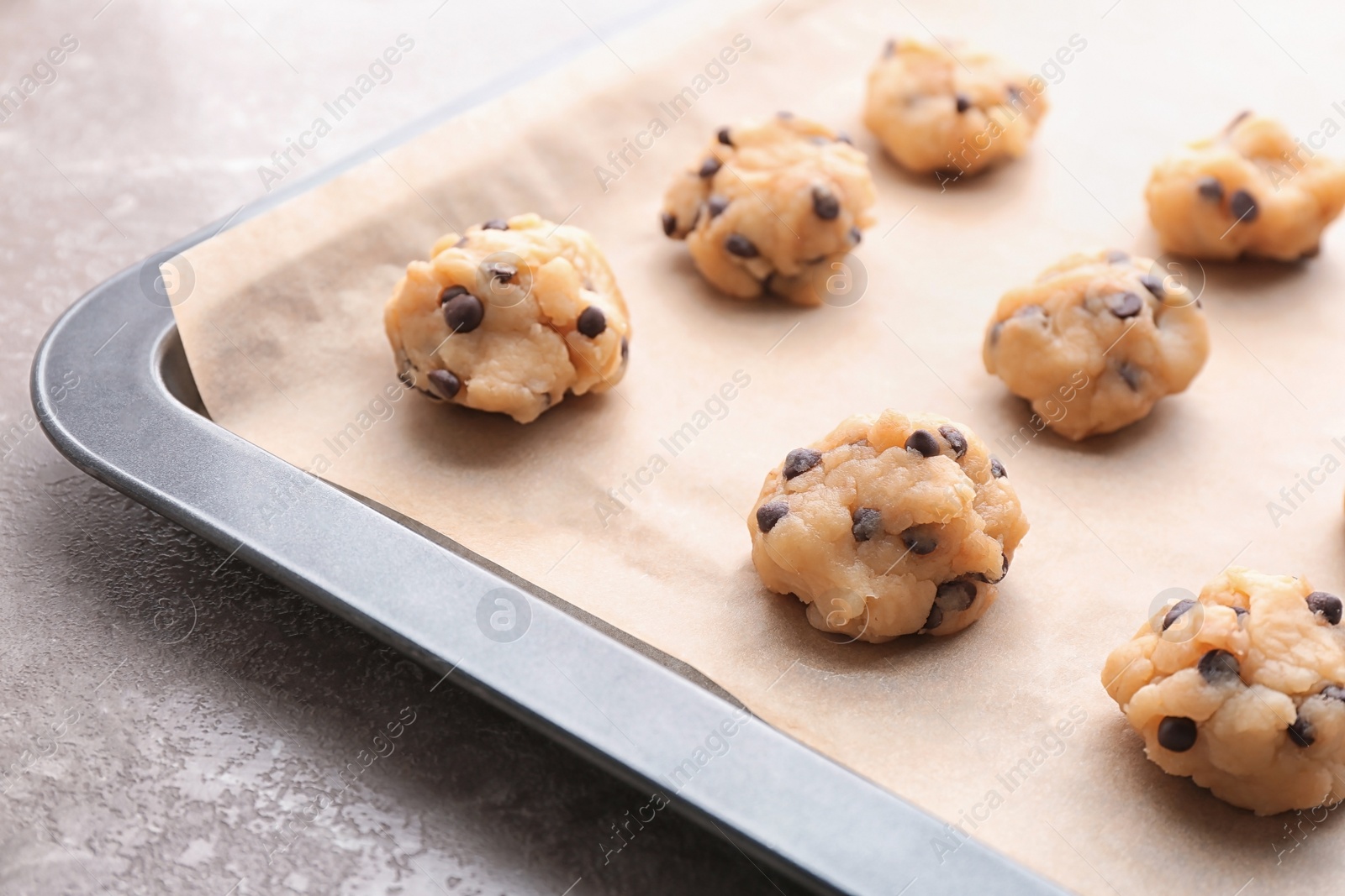 Photo of Cookie dough with chocolate chips on baking sheet, closeup