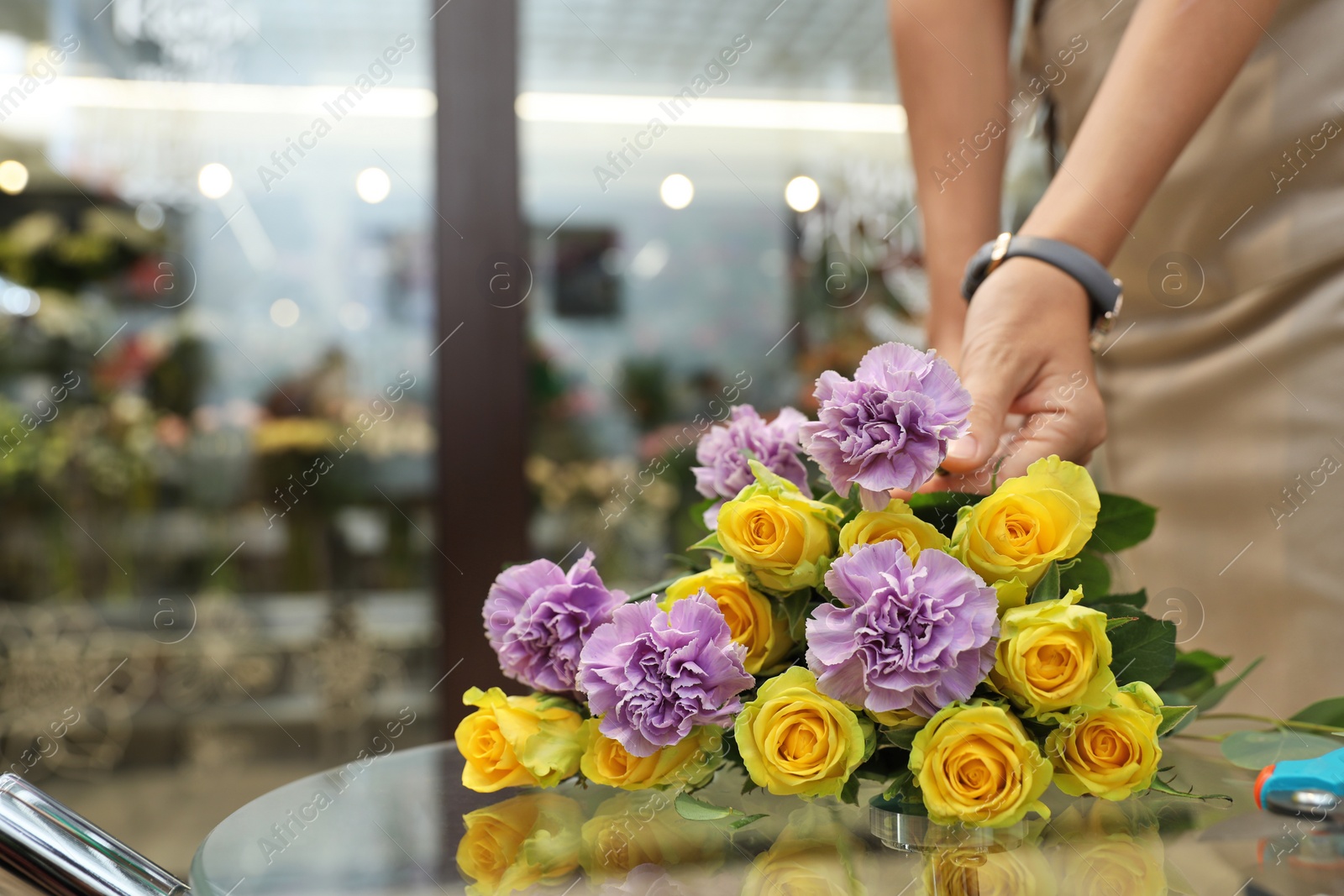 Photo of Female florist making beautiful bouquet in flower shop, closeup