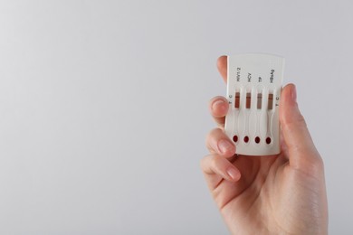 Woman holding disposable multi-infection express test on light background, closeup. Space for text
