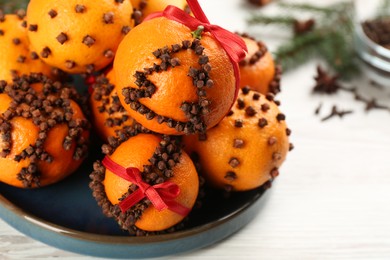 Pomander balls made of fresh tangerines and cloves on white table, closeup