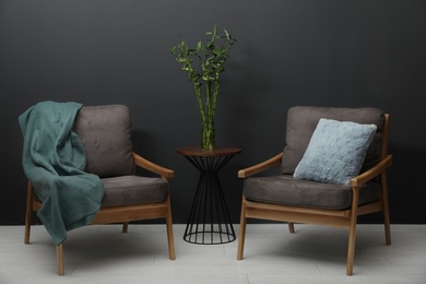 Modern living room interior with comfortable armchairs and green bamboo on table