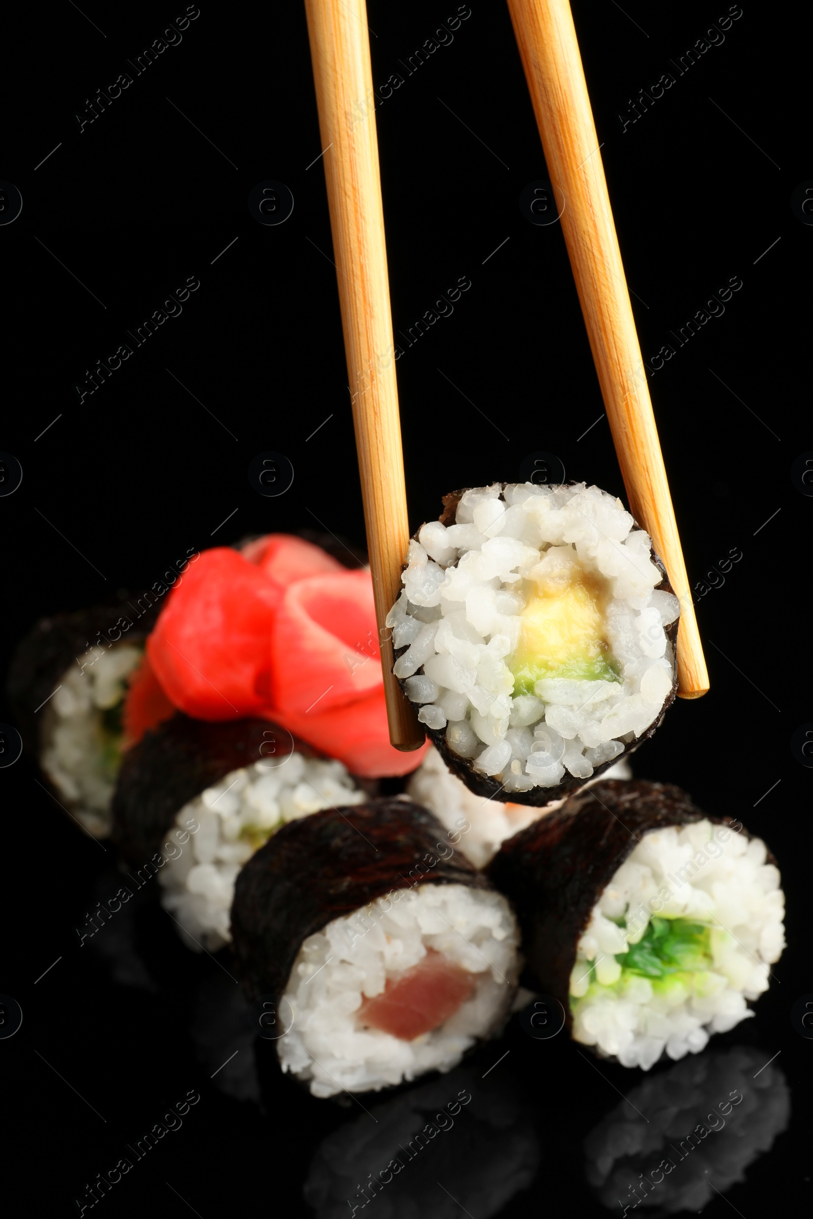 Photo of Set of delicious sushi rolls and chopsticks on black background