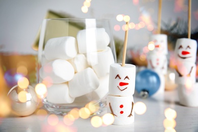 Image of Funny snowman made of marshmallows on white table. Bokeh effect