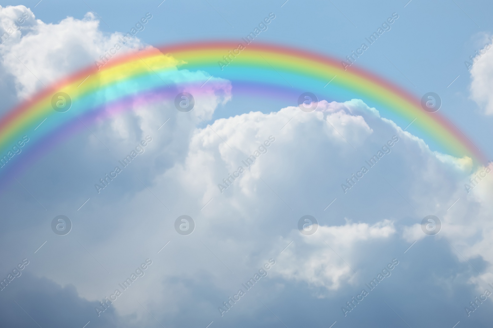 Image of Beautiful rainbow in blue sky with white clouds on sunny day