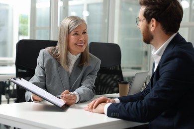 Photo of Lawyer with clipboard working with client at table in office