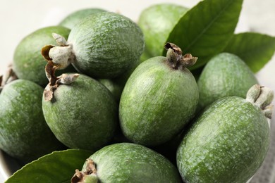 Photo of Delicious fresh feijoas and leaves on light background, closeup