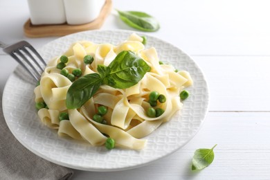 Photo of Delicious pasta with green peas served on white wooden table