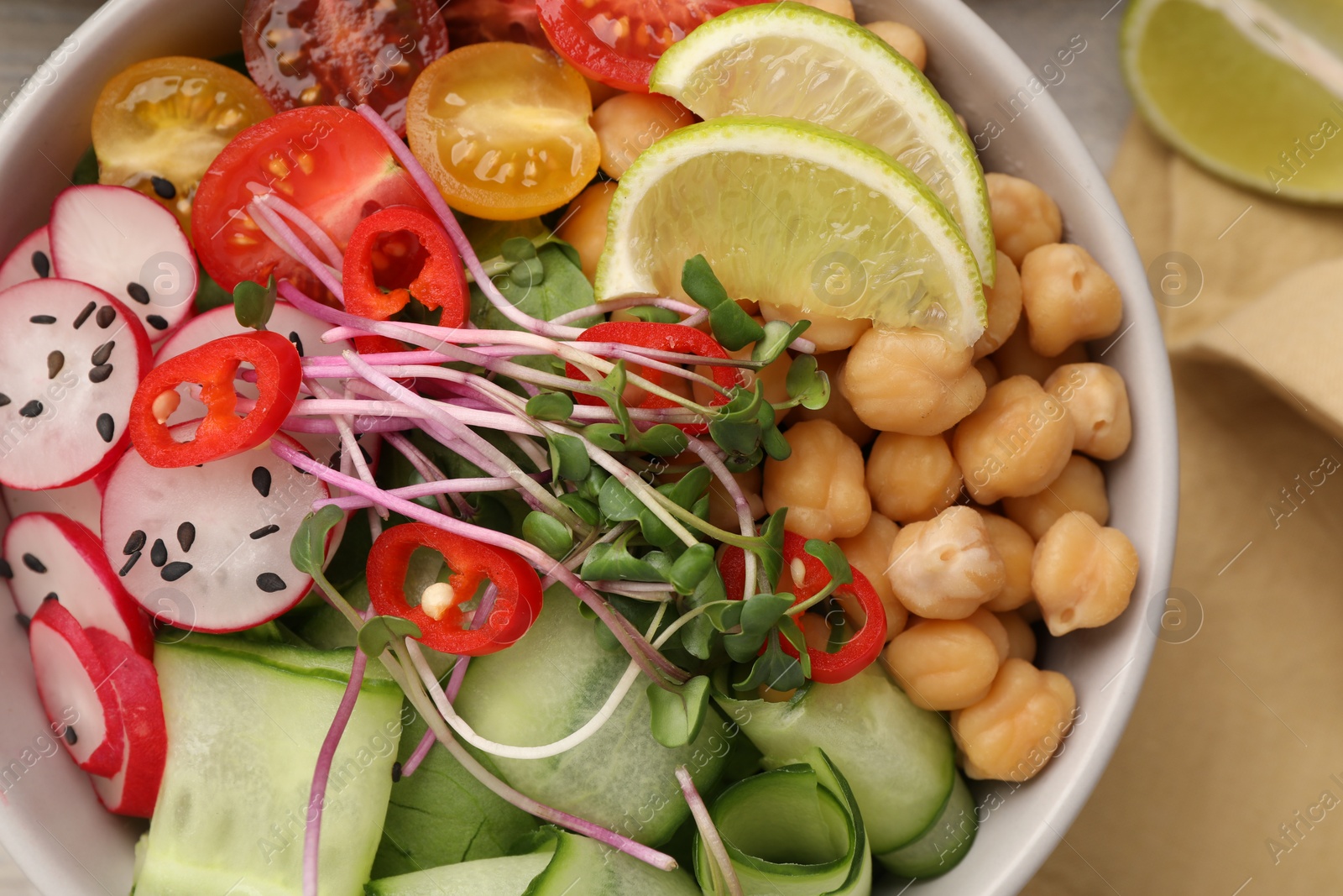 Photo of Bowl with many different vegetables on white wooden table, flat lay. Vegan diet