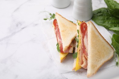 Delicious sandwiches with bacon on white marble table, closeup. Space for text