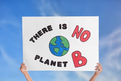 Image of Protestor holding placard with text There Is No Planet B against blue sky, closeup. Climate strike