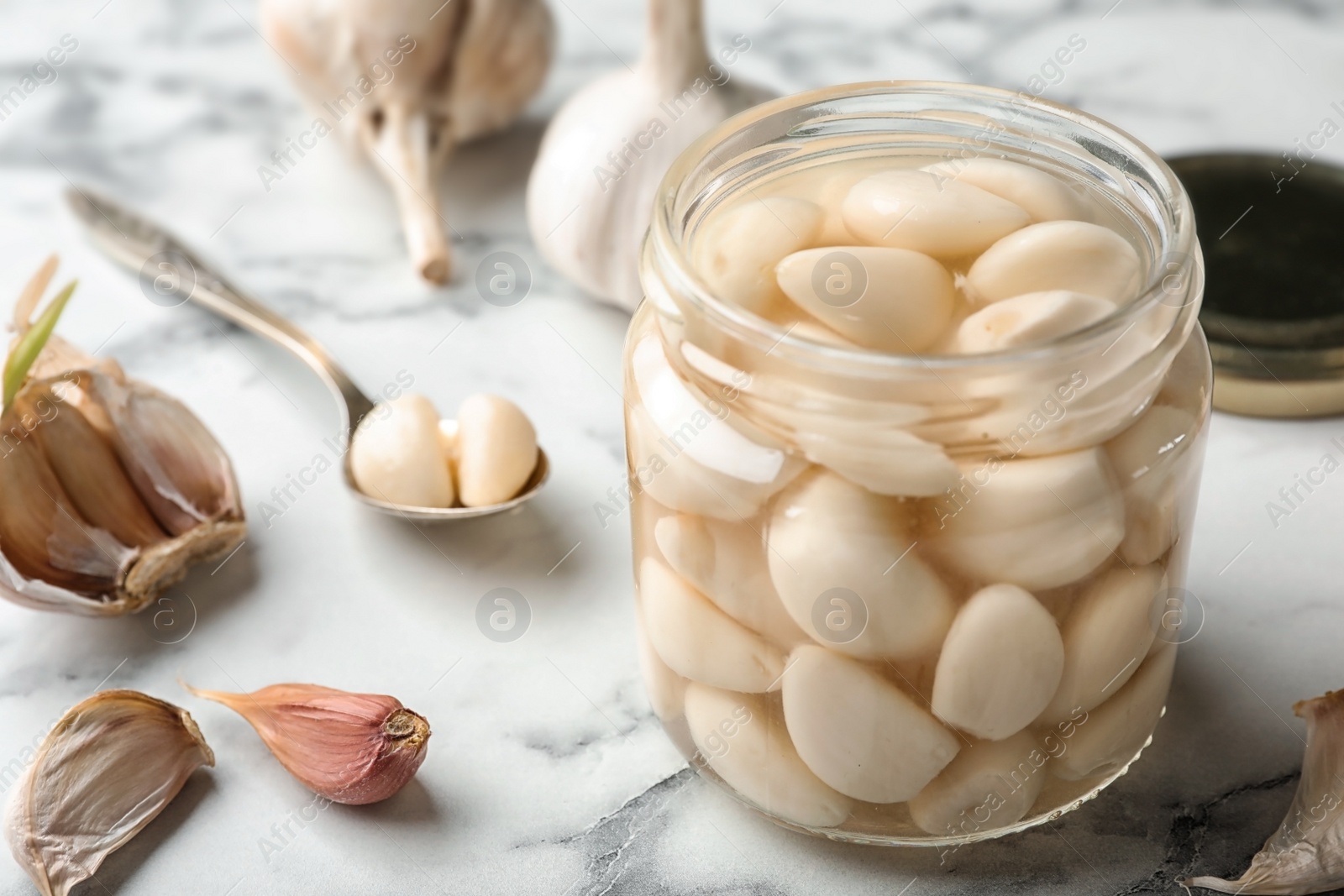 Photo of Preserved garlic in glass jar on table, closeup. Space for text