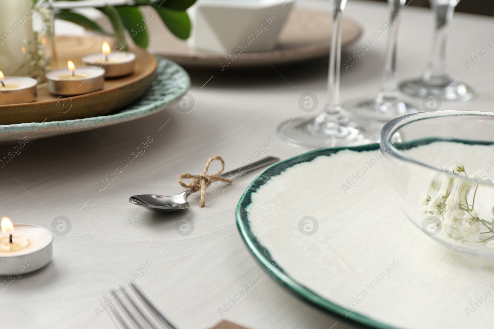 Photo of Elegant spoon tied with twine on white wooden table, closeup. Festive setting