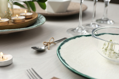 Elegant spoon tied with twine on white wooden table, closeup. Festive setting