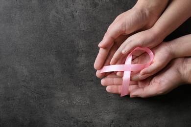 Woman and girl holding pink ribbon on grey background, top view with space for text. Breast cancer awareness