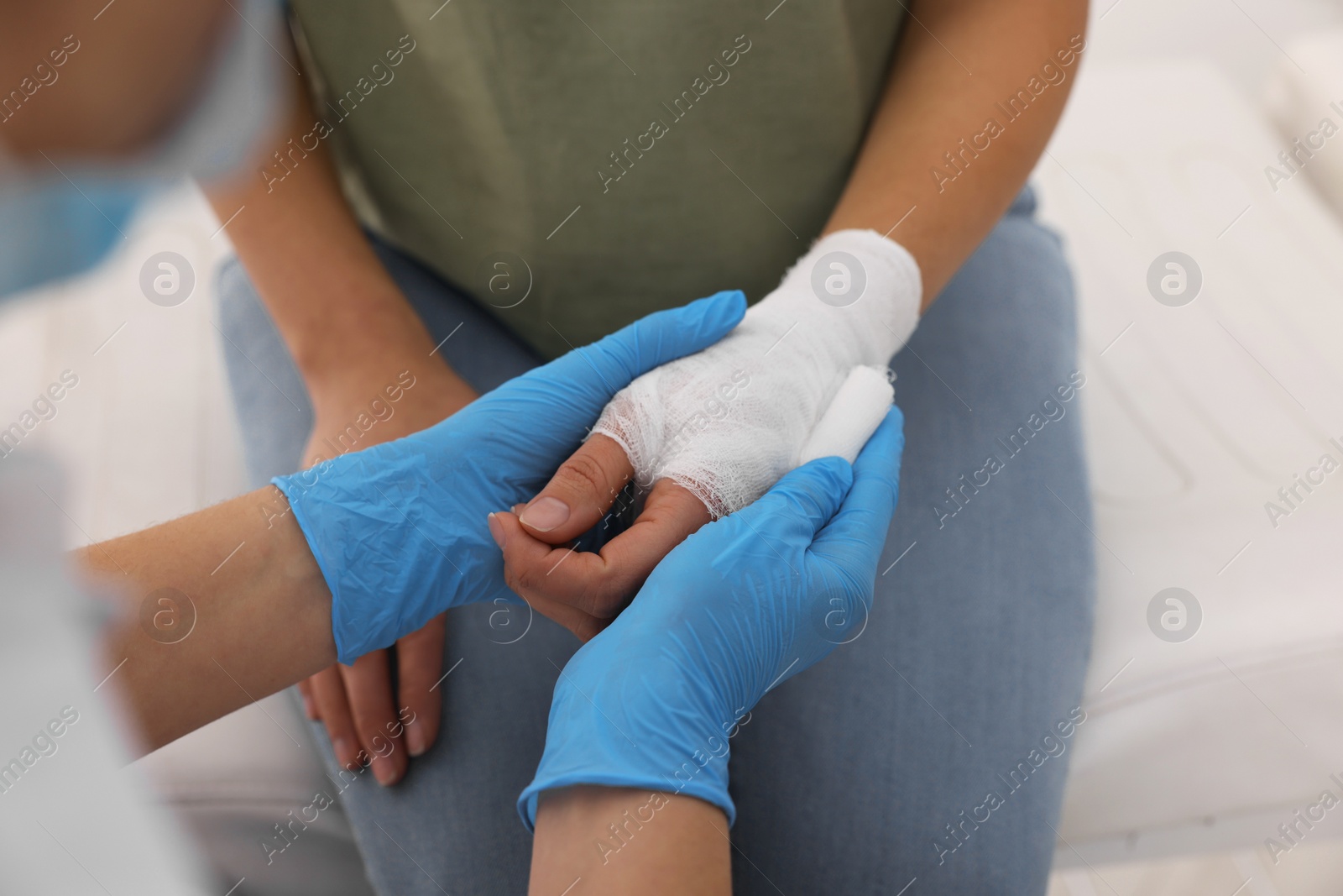 Photo of Doctor bandaging patient's burned hand indoors, closeup