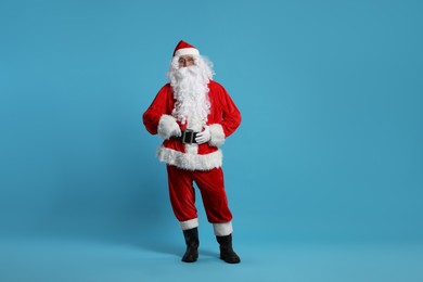 Photo of Merry Christmas. Santa Claus posing on light blue background