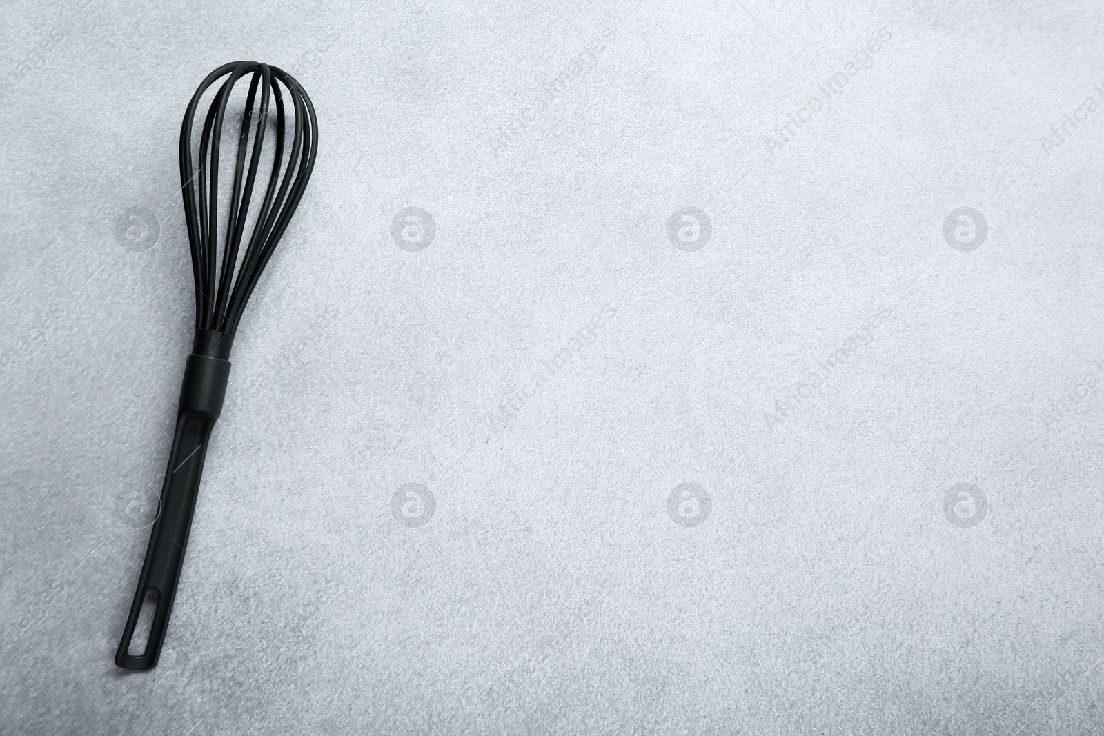 Photo of Plastic whisk on gray table, top view. Space for text