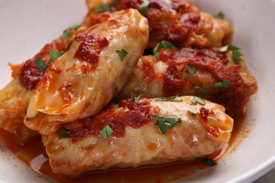 Photo of Delicious stuffed cabbage rolls cooked with homemade tomato sauce in bowl, closeup