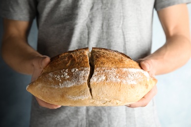 Photo of Man holding whole wheat bread on grey background, closeup