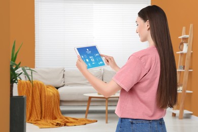 Woman using smart home control system via application on tablet indoors