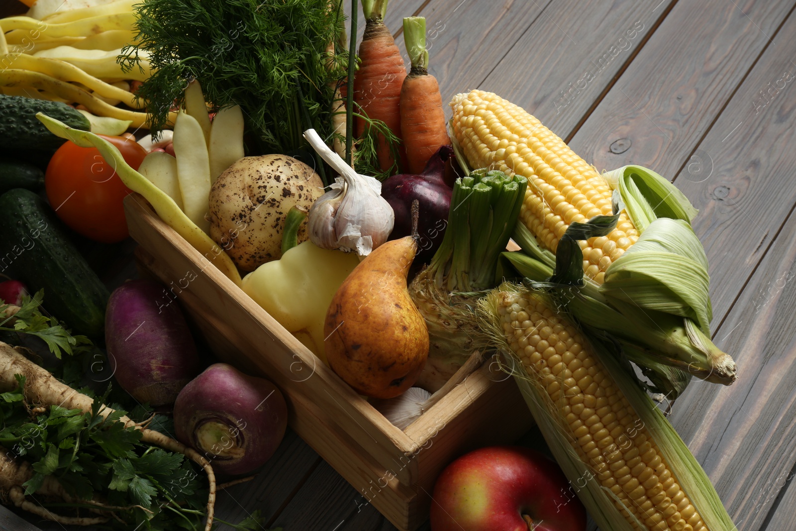 Photo of Different fresh vegetables with crate on wooden table, closeup. Farmer harvesting