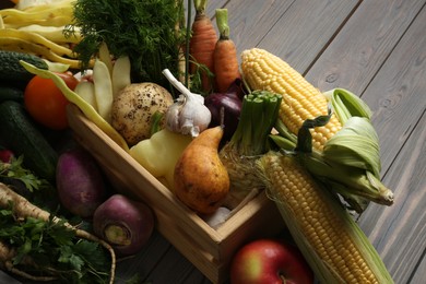 Photo of Different fresh vegetables with crate on wooden table, closeup. Farmer harvesting