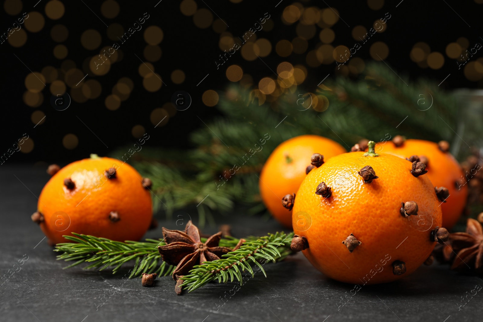 Photo of Delicious fresh tangerines with cloves on black table. Christmas celebration