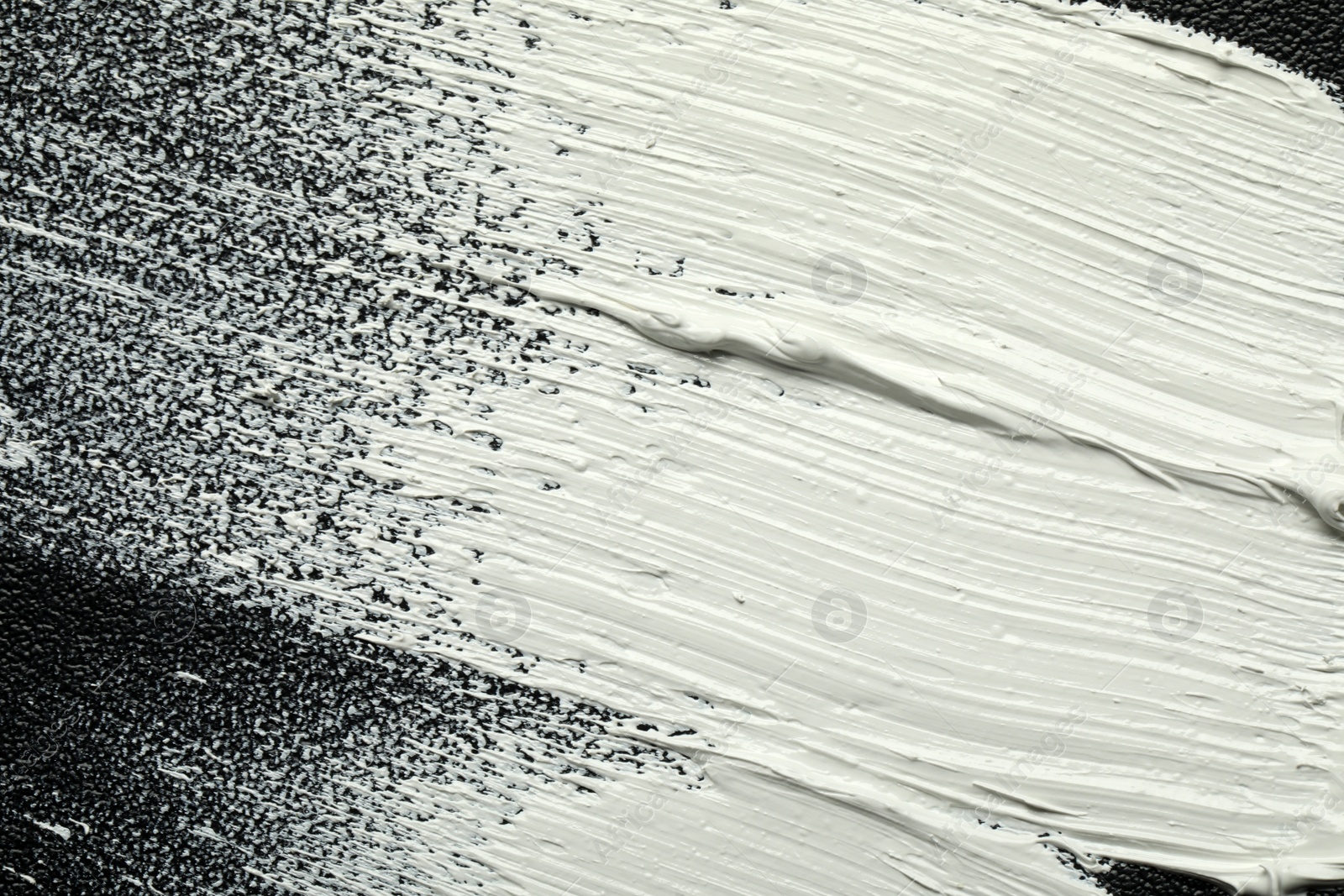Photo of Strokes of white oil paint on black canvas, closeup