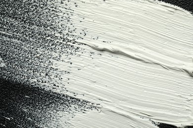 Strokes of white oil paint on black canvas, closeup