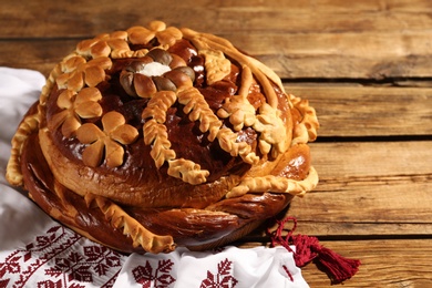 Photo of Korovai with rushnyk on wooden table. Ukrainian bread and salt welcoming tradition