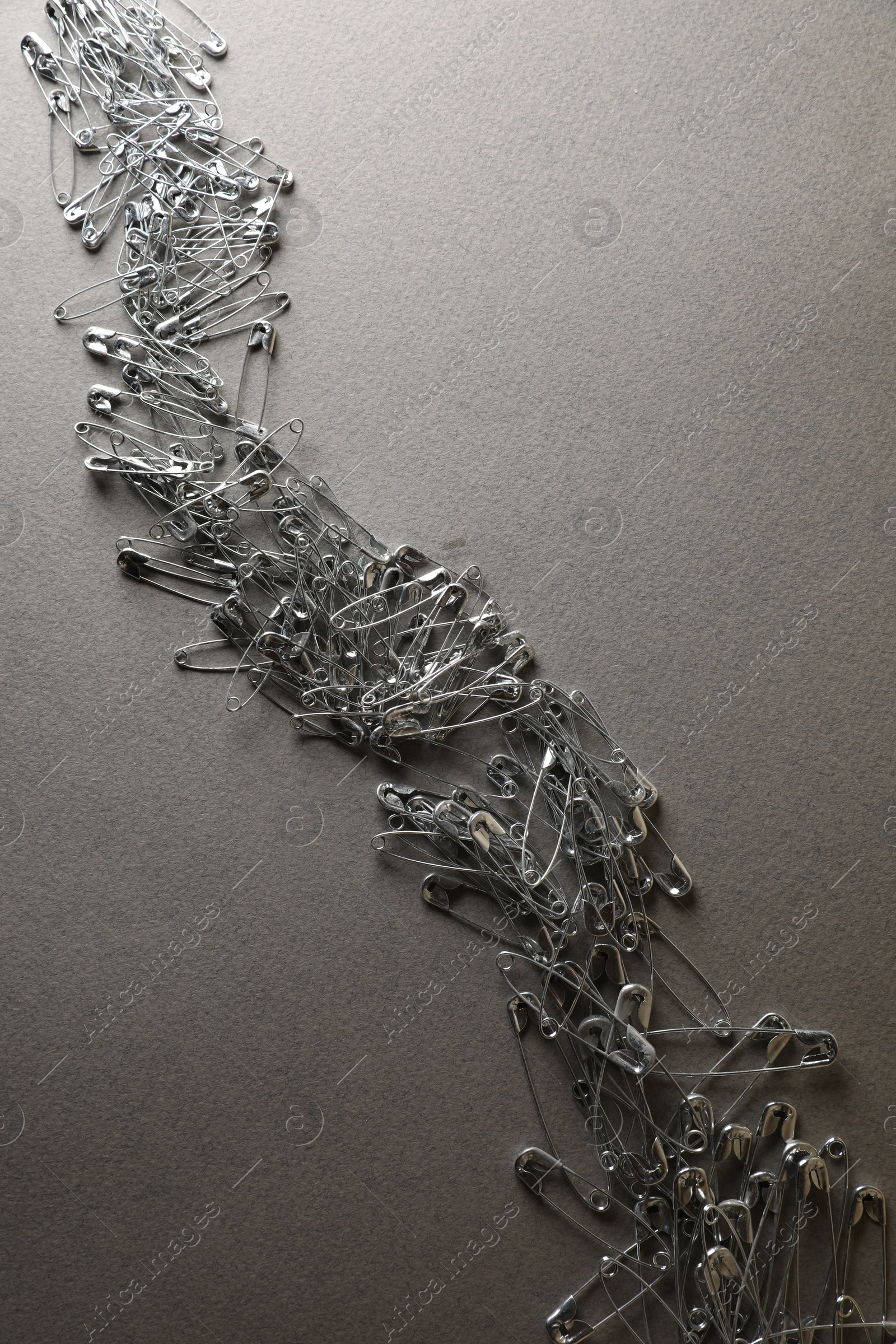 Photo of Many safety pins on light grey textured background