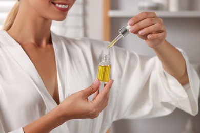 Photo of Woman with cosmetic serum in her hands indoors, closeup