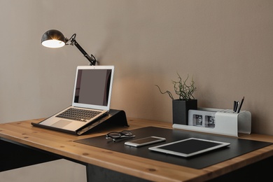 Modern workplace interior with laptop and devices on table. Space for text